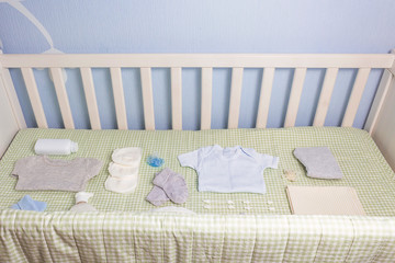 Set of clothing and body care supplies for newborns in baby crib. Collect the bag in the maternity hospital. Accessories for baby care. Preparation before your baby arrives.