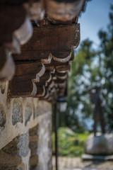 Detail of an old wooden house with stone wall.