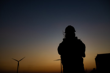 Silhouette of women engineer working and holding the report at wind turbine farm Power Generator Station on mountain,Thailand people