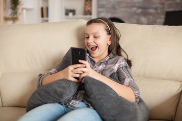 Happy little girl sitting on the couch in living room