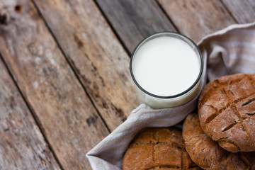 Glass of fresh milk and round brown rye flatbread on a rustic wooden table. Vegetable milk, vegan milk, Kefir, or Turkish Ayran drink for helthy eating. Space for text. Top view