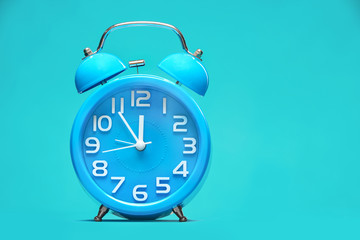 Blue round retro alarm clock on a blue background in the studio