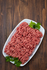 ground meat on white dish on brown wooden background