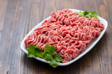 ground meat on white dish on brown wooden background