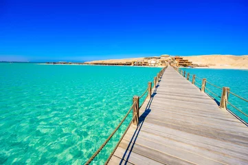 Fotobehang Wooden Pier at Orange Bay Beach with crystal clear azure water and white beach - paradise coastline of Giftun island, Mahmya, Hurghada, Red Sea, Egypt. © Simon Dannhauer