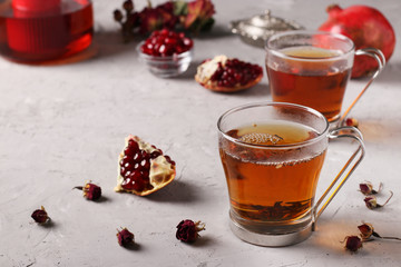 Pomegranate tea in two transparent cups on a gray concrete background, warming wellness drink