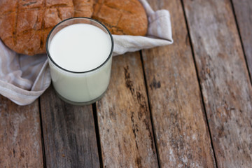 Glass of fresh milk and round brown rye flatbread on a rustic wooden table. Vegetable milk, vegan milk, Kefir, or Turkish Ayran drink for helthy eating. Space for text. Top view