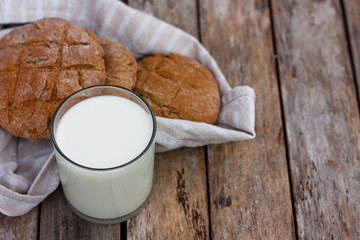 Glass of fresh milk and round brown rye flatbread on a rustic wooden table. Vegetable milk, vegan milk, Kefir, or Turkish Ayran drink for helthy eating. Space for text. Top view