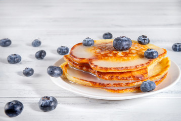 pancakes with fresh blueberries on a white plate on a white