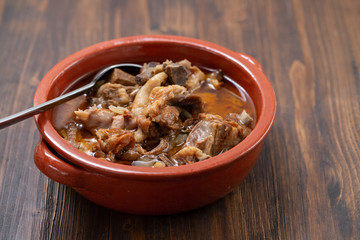 baked lamb with onion and pepper in the brown ceramic bowl