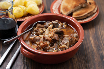 baked lamb with onion and pepper in the brown ceramic bowl