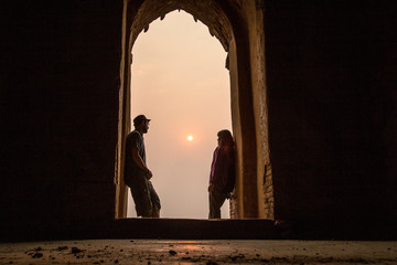 A couple at the gate at sunset in a temple in Bagan. Myanmar