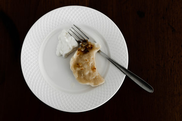 dumpling lies in a white plate on a wooden table background,a dumpling sprinkled with fried qibula and svetana lies in a bowl,ready dumpling served on the table