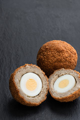 Scotch eggs on black stone background