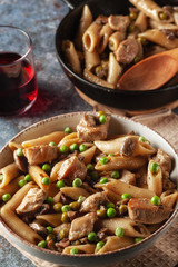 Homemade pasta with green peas, chicken and sauce on a dark background