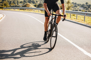 Close up of mature man with strong body wearing cycling clothing and sneakers, riding bike on...