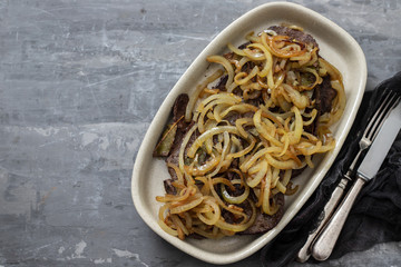 fried liver with onion on the dish on ceramic background