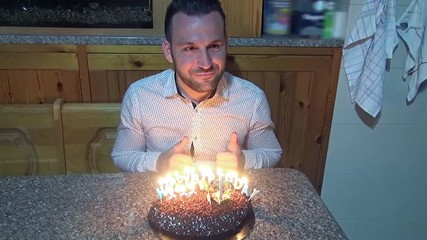 A young man in front of his birthday cake while a girl takes souvenir photos with her smartphone