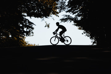 Active sportsman in silhouette riding bike on nature during summer day. Strong cyclist in...