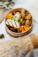 Vegetarian and vitamin-rich dish with tofu, beans and potatoes in eco-box, delivered by a delivery service, ordered online, decorated with bundles of straw on white wood, all in a Mediterranean style