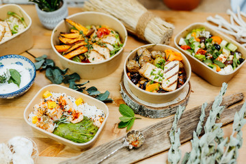 Various healthy and vitamin-rich dishes and food in an ecobox delivered by a delivery service, ordered online, decorated with bundles of straw, mussels and cacti, in a Mediterranean style