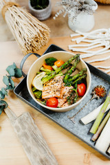 Vegetarian food rich in vitamins with salmon, asparagus, tomatoes and spices in eco box delivered by a delivery service, ordered online, decorated with raw asparagus on metal tablet