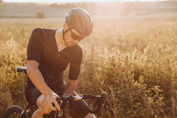 Professional cyclist in activewear, black helmet and sport glasses taking break from riding on...