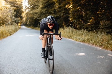 Sporty bearded man in protective helmet and mirrored glasses riding bike in half-bent pose for...