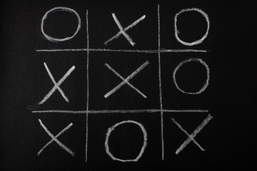 top view of tic tac toe game on blackboard with chalk grid, naughts and crosses