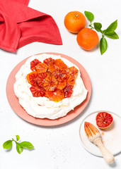 Homemade meringue pie decorated with fresh blood orange slices. Pavlova cake, traditional Australian dessert. Selective focus.