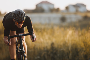 Close up of male athlete in cycling clothes, black helmet and protective glasses looks very...