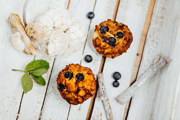 Healthy muffins with coconut flour and blueberries on light wooden plate decorated with mint an conch shells