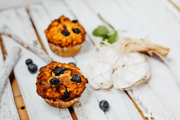 Healthy muffins with coconut flour and blueberries on light wooden plate decorated with mint an conch shells