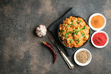.Chicken tikka masala traditional Asian spicy meat food with rice tomatoes and cilantro in a black bowl on dark background.