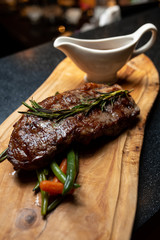 Grilled meatsteak with a sprig of rosemary on a wooden board