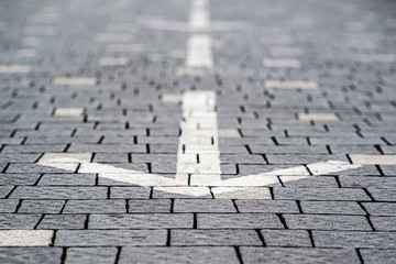 Street arrow on tile road. Backward movement. Traffic arrow.