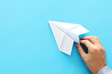 concept image of person hand directing paper plane over blue background