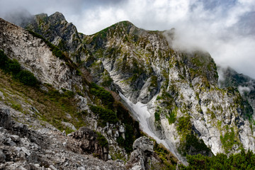 Fototapeta na wymiar 夏の北アルプス後立山連峰、唐松岳へ向かう八方尾根からの天狗の頭と天狗尾根に雲がかかる