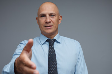 Satisfied businessman holds out his hand to secure a deal.