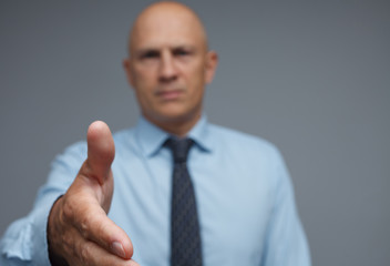 Serious businessman holds out his hand to secure a deal.