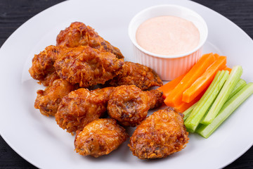 Fried legs and wings with breading, served with sauce and vegetables
