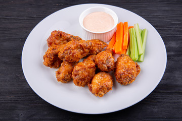 Fried legs and wings with breading, served with sauce and vegetables