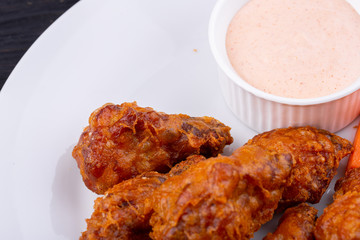 Fried legs and wings with breading, served with sauce and vegetables