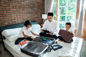 Father and her child prepare clothes and suitcase for carried when mudik go to the village