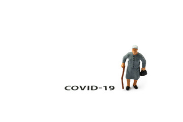 Old woman and coronavirus outbreak. Small figurine and text about Covid-19 on white background.