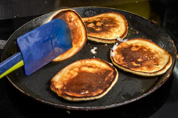 Pancakes are fried in a pan on an induction stove