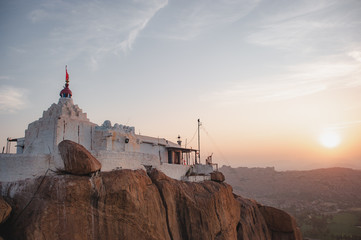 Hanuman's white temple on the top of the hill, where according to legend, the god of the Hindu pantheon Hanuman was born, in the rays of the rising sun against the background of the valley