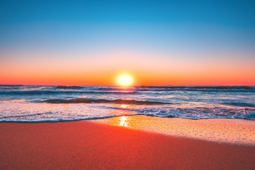 Beach sunrise or sunset with clear blue sky and rising sun