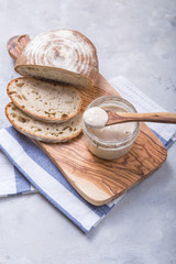 Fresh homemade bubbly sourdough starter, a fermented mixture of water and flour to use as leaven for bread baking, on wooden table