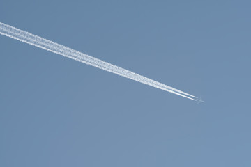 Passenger plane with contrail in the blue sky.